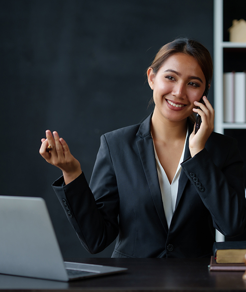 Lawyer concept. Beautiful Asian lawyer is talking on the phone with a client and using a laptop to review legal matter to support the case file consequences of legal action on client.